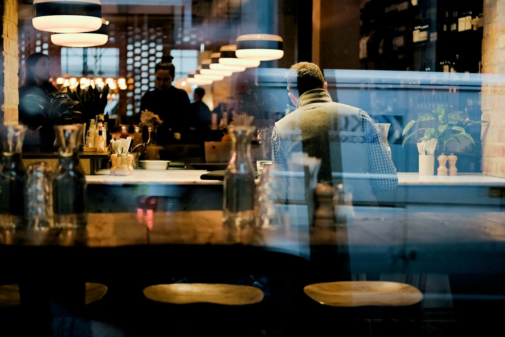 Cafe owner in a white shirt standing behind the counter of a small cafe