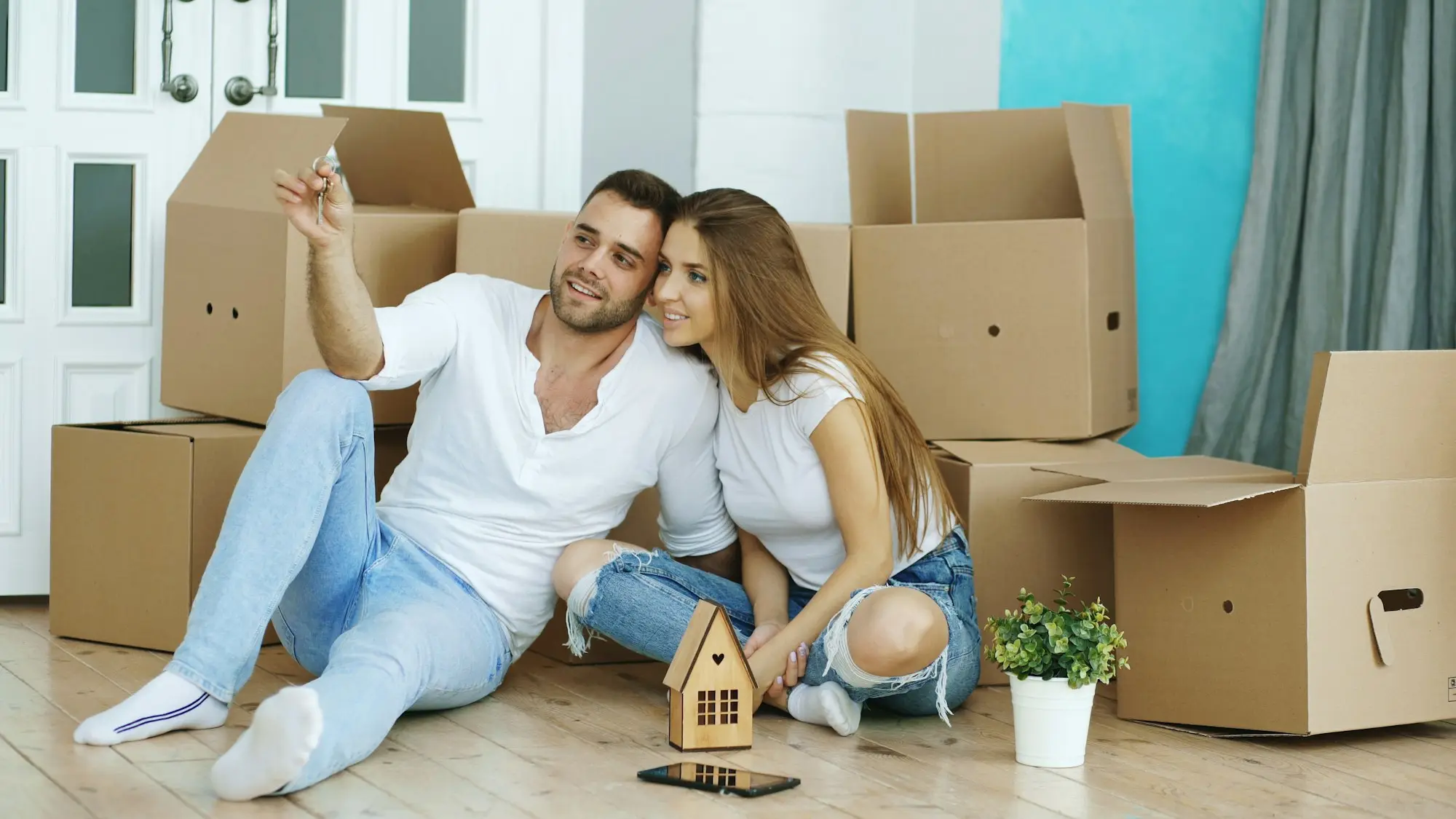 Couple sitting on the floor surrounded by moving boxes